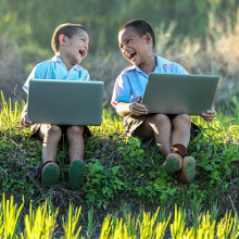 Dous nenos usando dous portátiles.